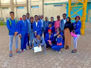 Groupe d’étudiants en blazer bleu posant devant un bâtiment, l’un d’eux tenant une attestation.
